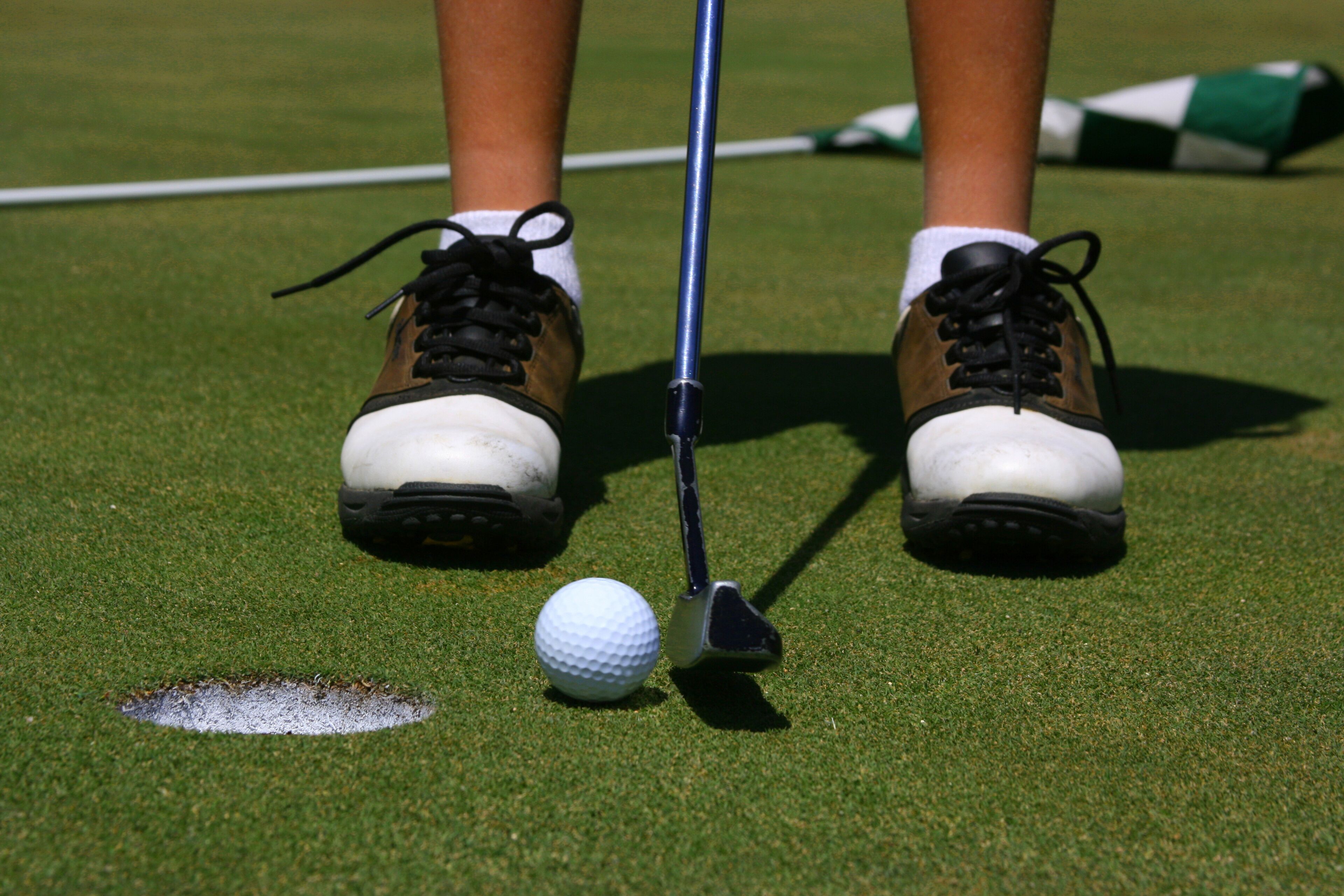 A golfer about to putt with flag in the background