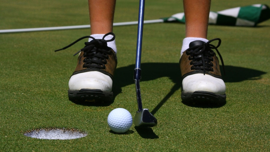 A golfer about to putt with flag in the background