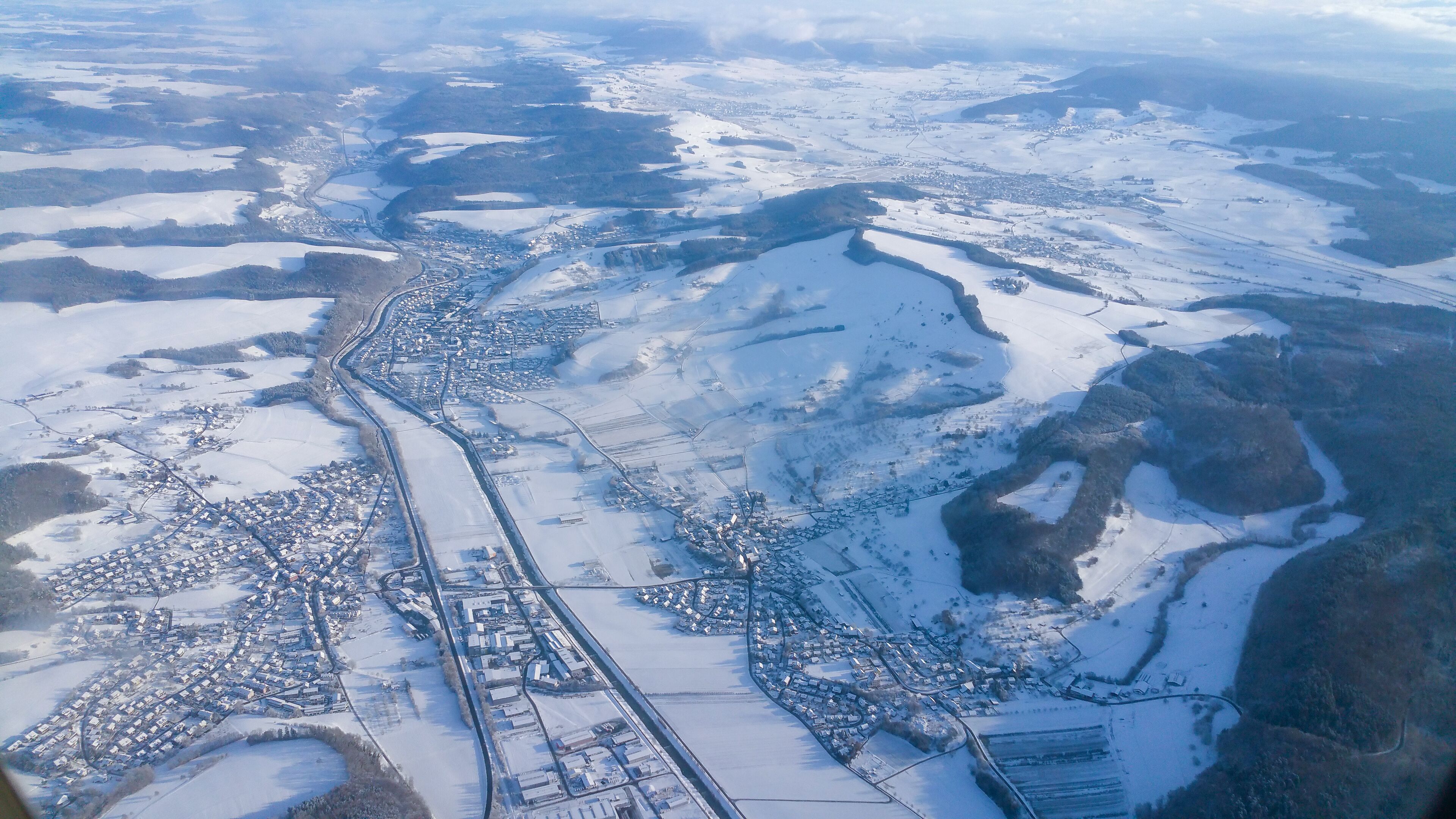 An aerial view of a snow-covered town with a river running through it.