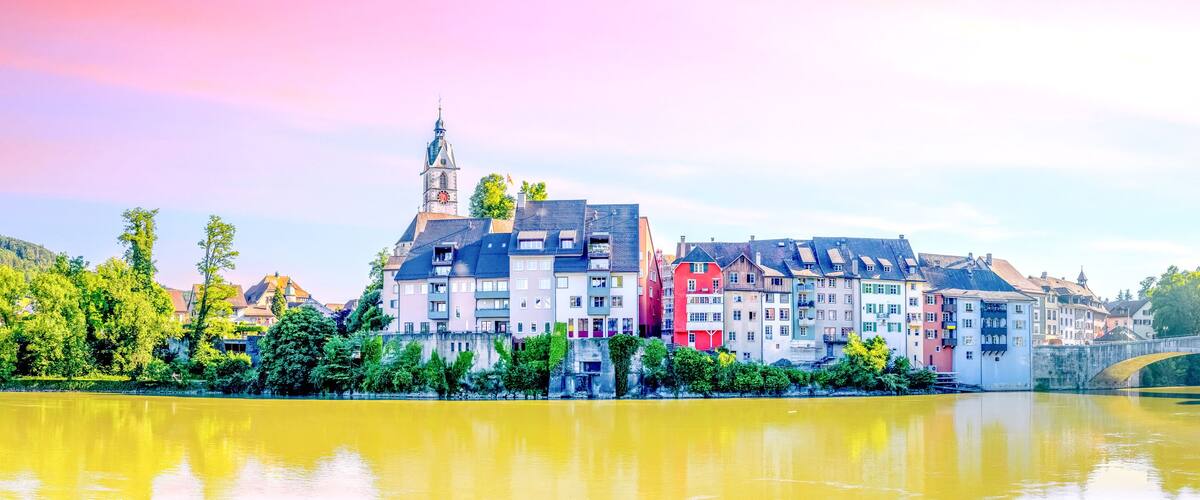 A river with a bridge, colorful buildings, and a church tower.