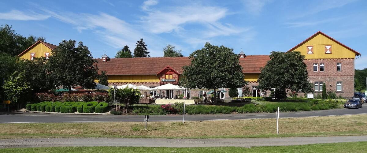 A yellow building with a red roof, surrounded by trees and a well-maintained lawn.