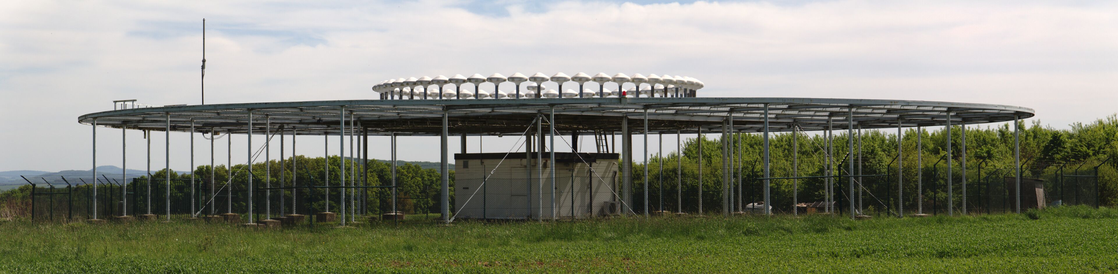 A large circular structure with a central building and multiple satellite dishes on its perimeter.