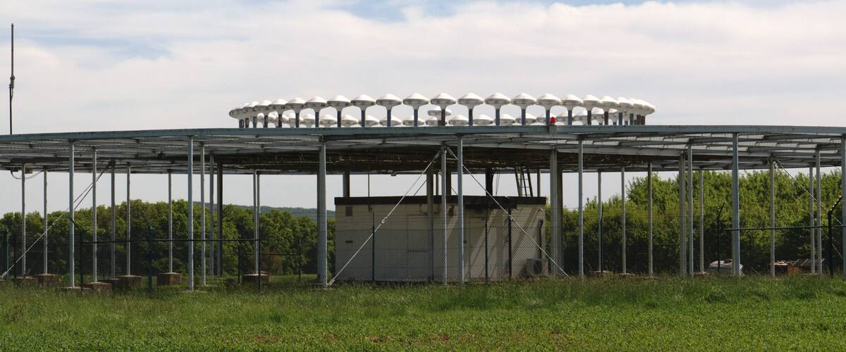 A large circular structure with a central building and multiple satellite dishes on its perimeter.