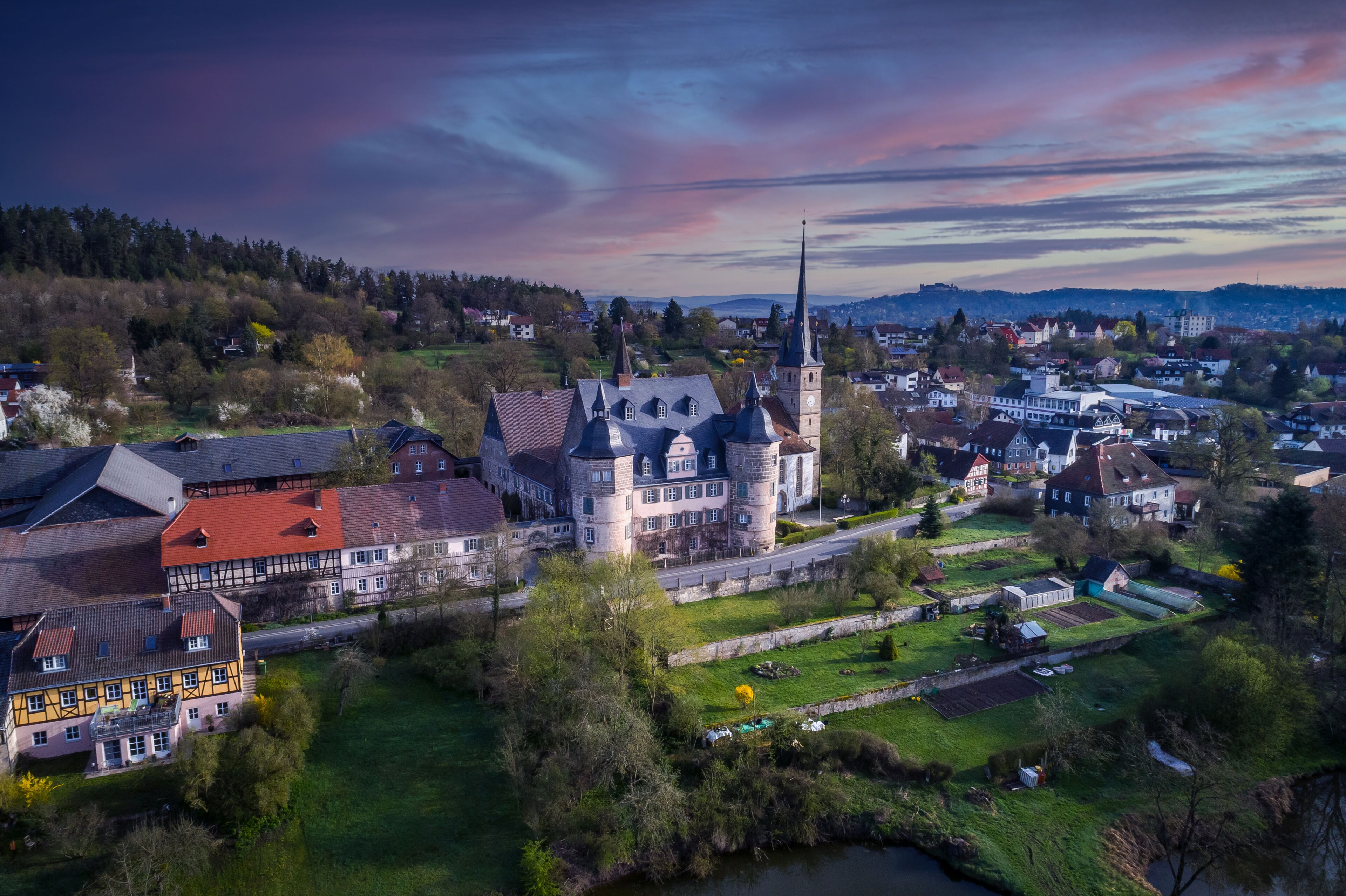 A historic town with a prominent church tower, traditional buildings, and a river.