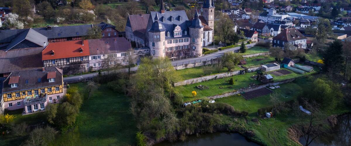 A historic town with a prominent church tower, traditional buildings, and a river.