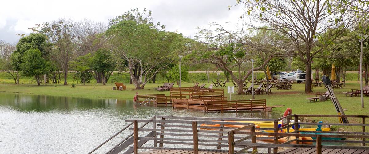 A lakeside park with wooden docks, benches, and picnic tables.