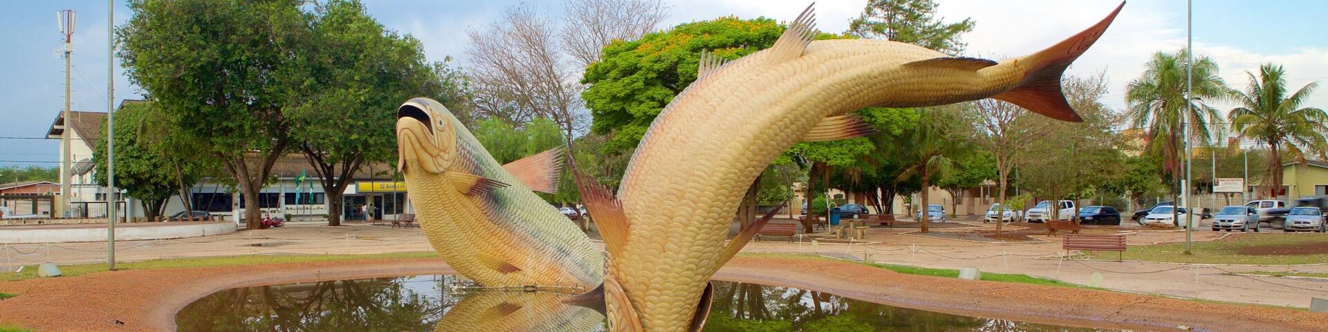 Una gran escultura de pez en un parque, con un estanque que refleja la escultura.