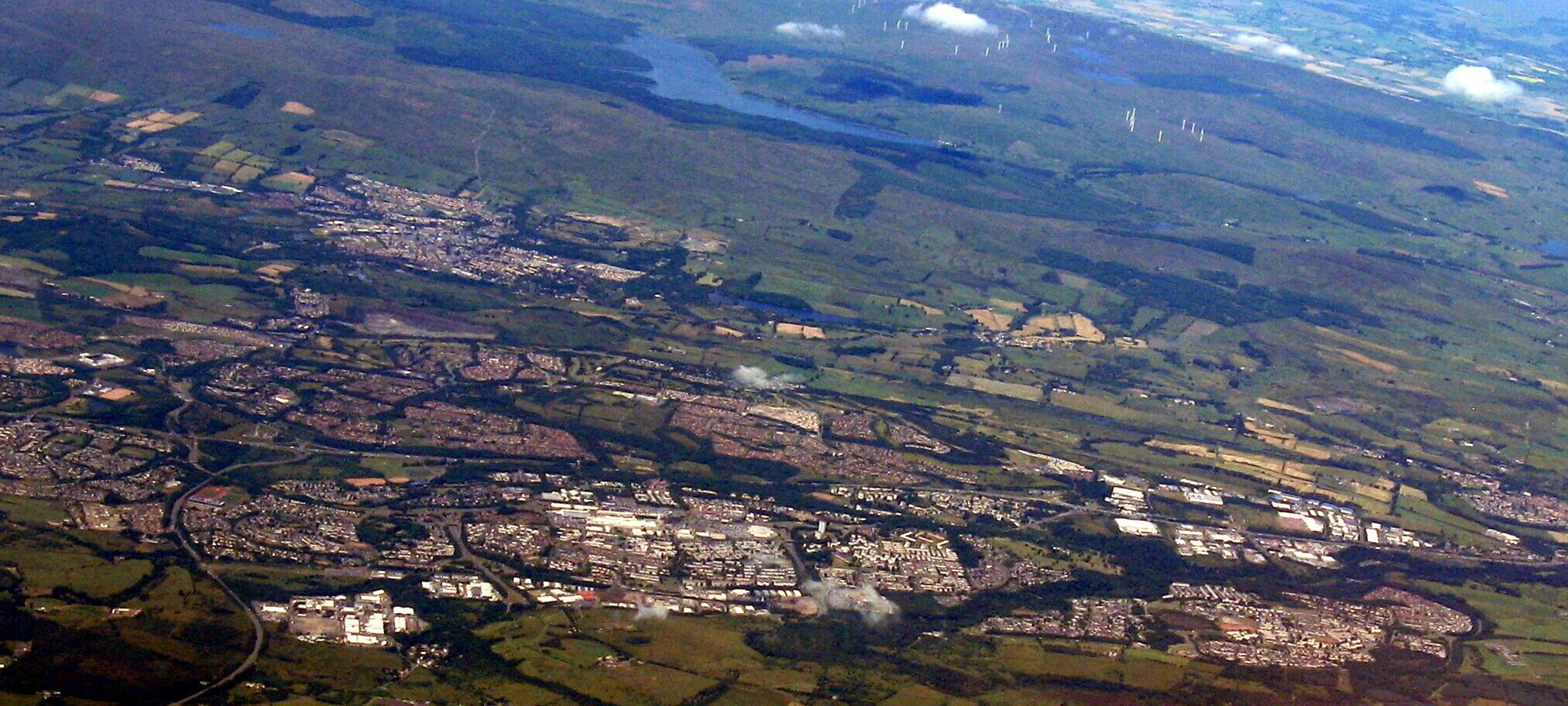 Looking northwest from over North Lanarkshire. The main built-up area across the lower centre is Cumbernauld; beyond and a little left is Kilsyth and beyond that are the Kilsyth Hills and the Carron Valley Reservoir.