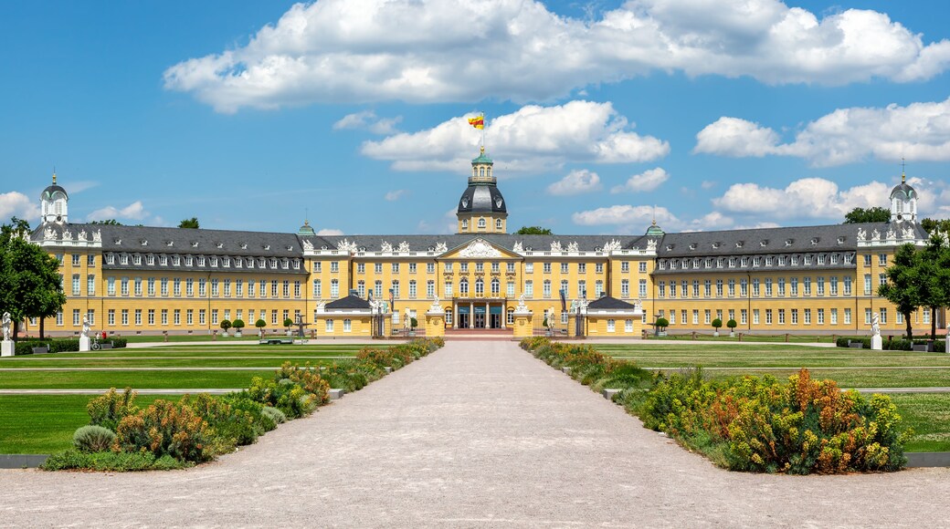 Un grand bâtiment jaune, doté d’un dôme central et de deux tours, entouré d’une pelouse bien entretenue et d’un chemin de gravier menant à l’entrée.