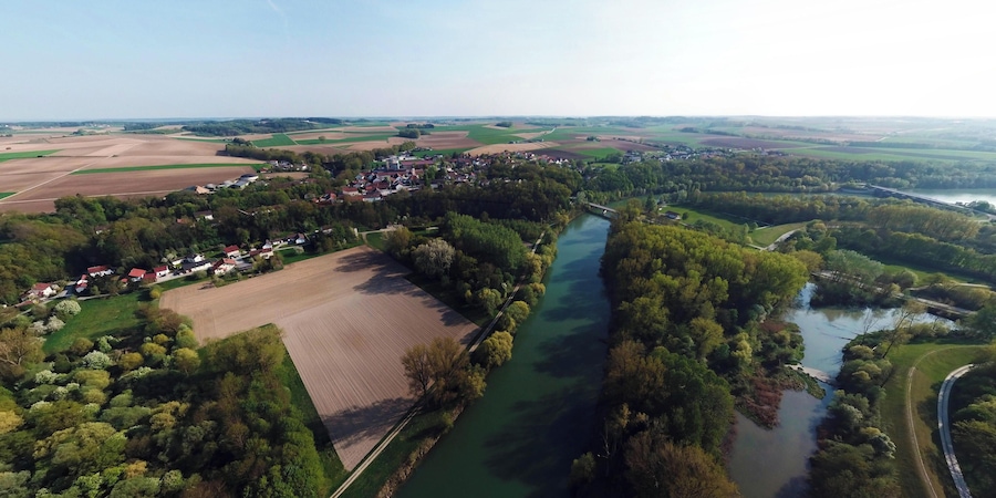 An aerial view of a rural landscape with a river, fields, and a small village.