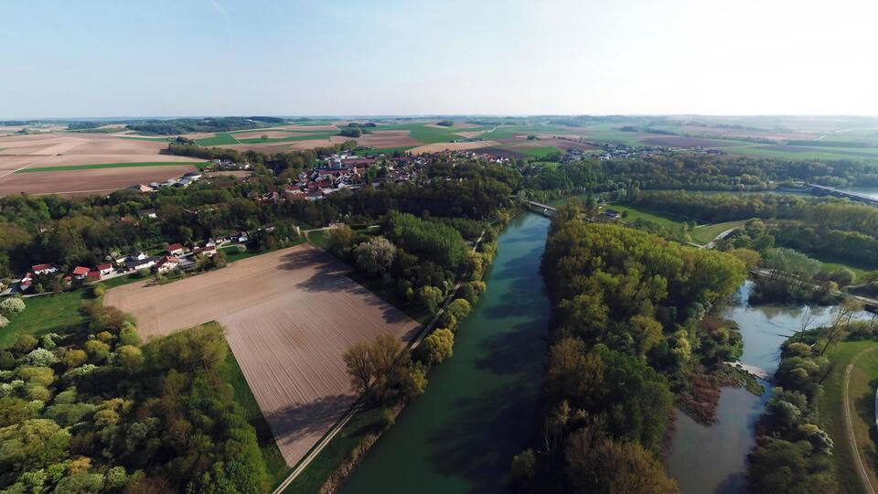 An aerial view of a rural landscape with a river, fields, and a small village.
