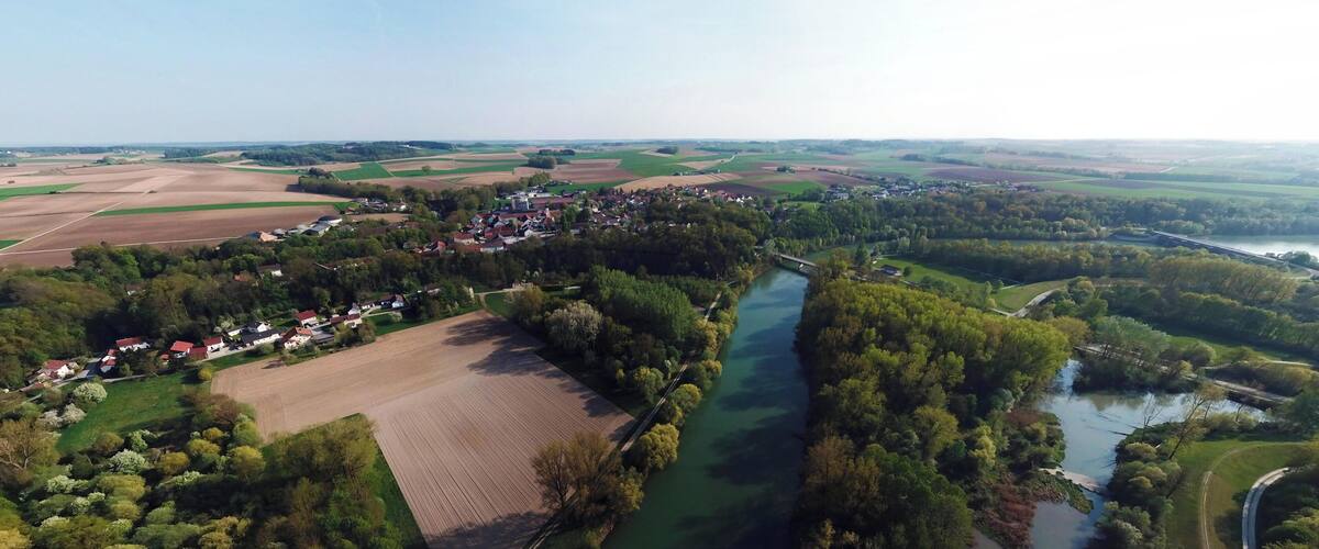 An aerial view of a rural landscape with a river, fields, and a small village.