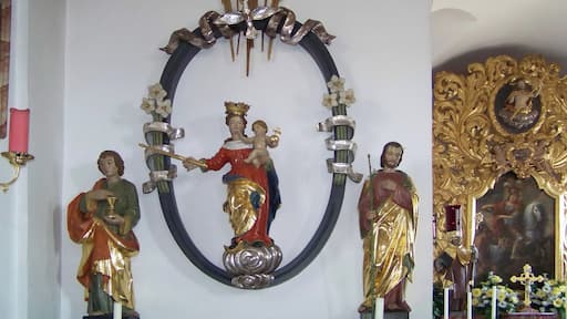 Bad Abbach, Dünzling, Marienplatz 4. Katholische Kirche St. Martin. Mittelalterlich, 1711/12 erweitert, Turmaufbau 1712. Linker Seitenaltar St. Maria. Figur Patrona Bavaria im ovalen Rahmen, um 1510. Darüber zeigt die Hand Gottes aus einer Wolke auf den Heiligen Geist, der als silberne Taube dargestellt ist. Seitenfiguren links St. Johannes Evangelist mit Kelch und St. Josef mit Lilie rechts.