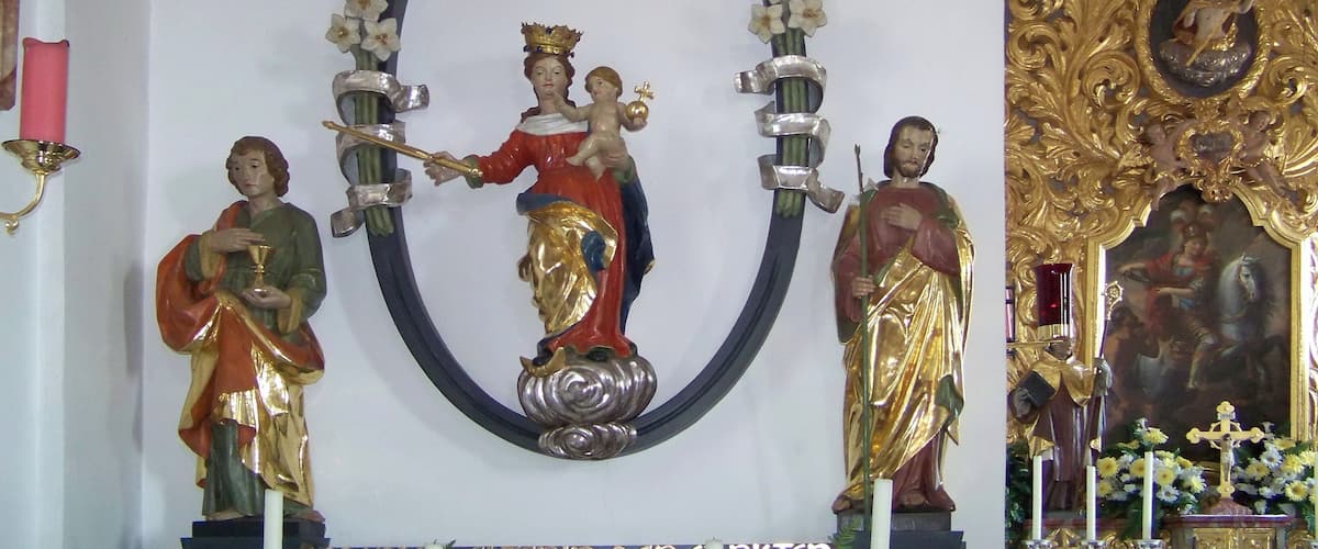 A religious statue with a halo, surrounded by flowers and candles.