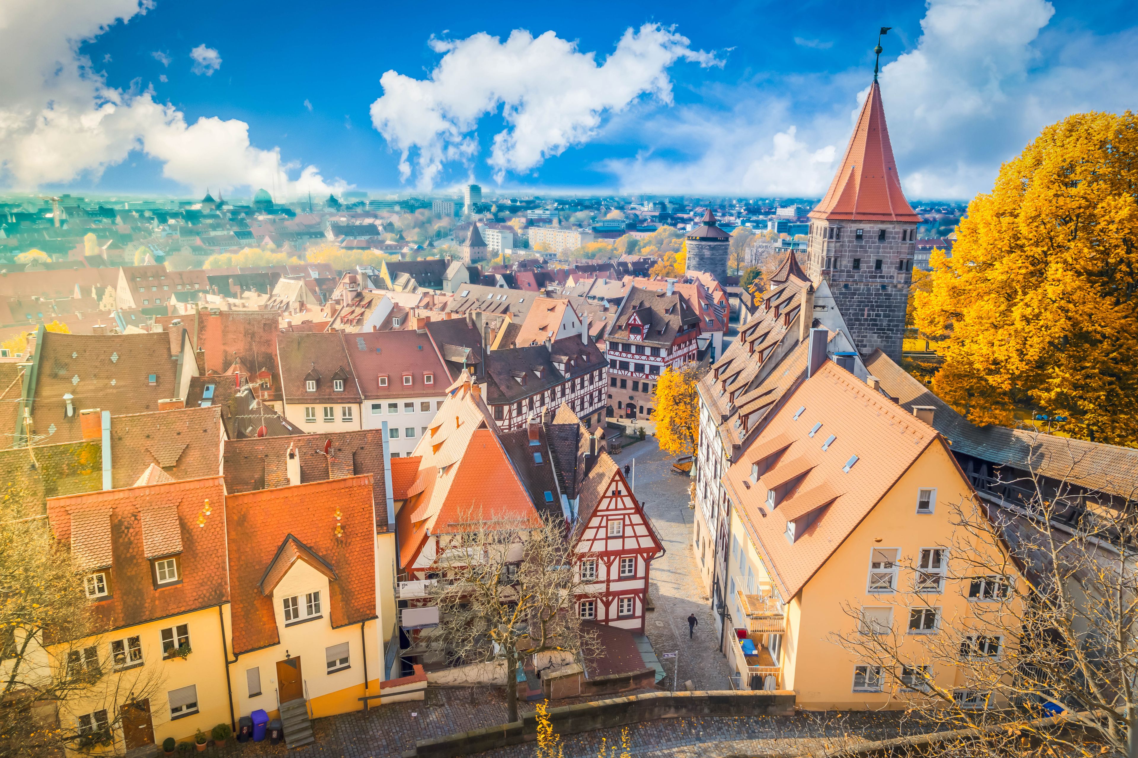 A town with traditional architecture, a prominent tower, and autumn foliage.