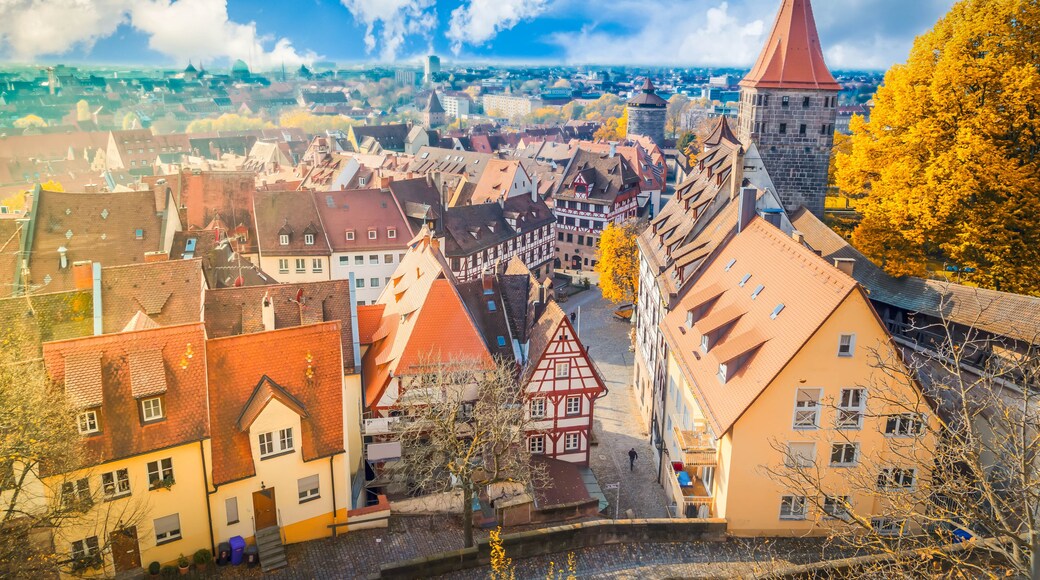 A town with traditional architecture, a prominent tower, and autumn foliage.