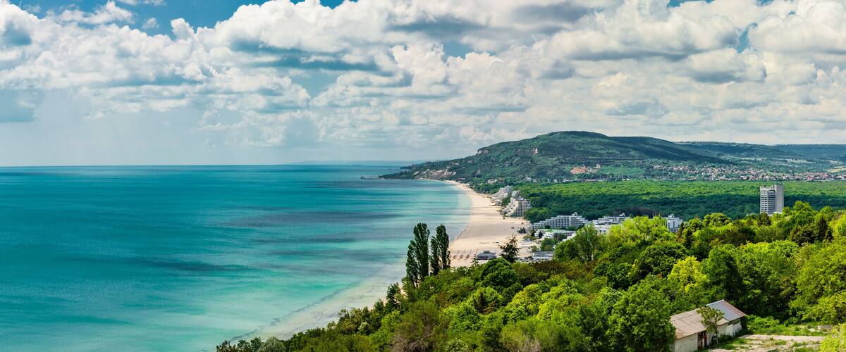 Paisatge costaner amb platja, muntanya i vila.