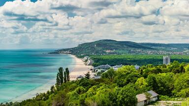 Paisagem costeira com praia, montanha e uma cidade.