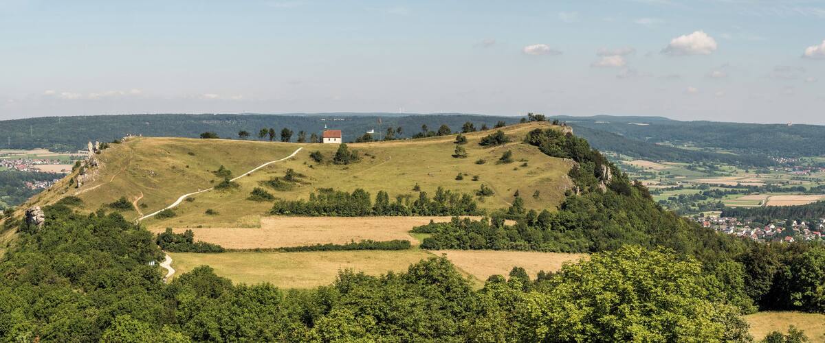 A hilltop with a small building, a winding path, and a distant town.