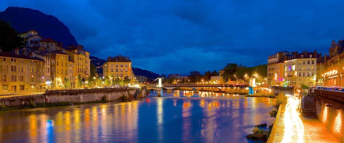 A river at dusk with a bridge and buildings along the banks.
