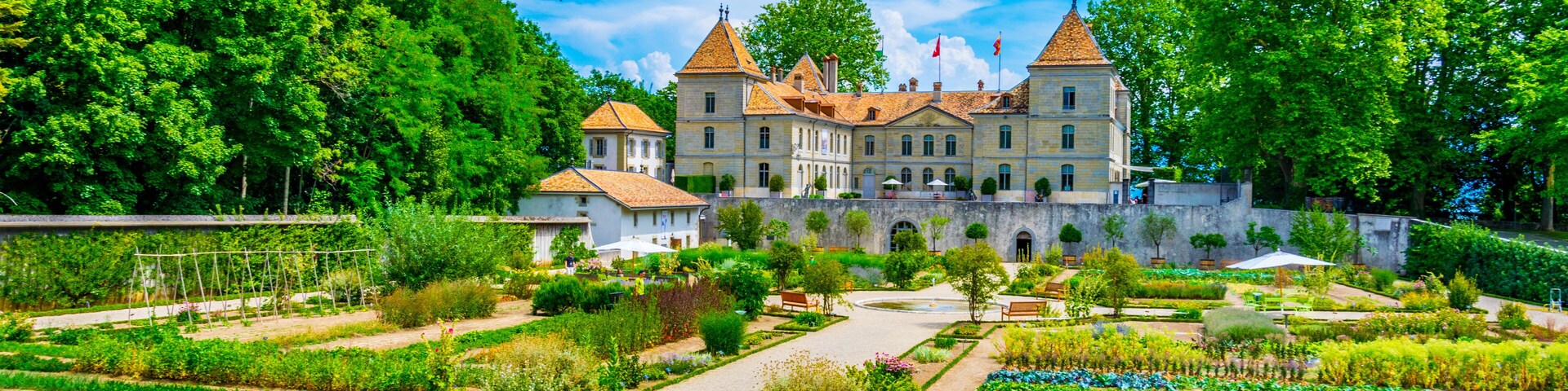 Um edifício grande e histórico com um jardim na frente.