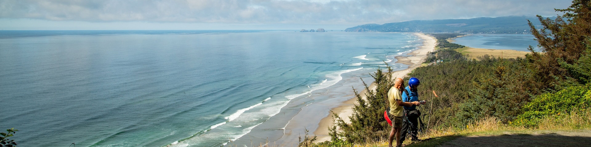Trilha costeira com vista para o oceano e a praia.