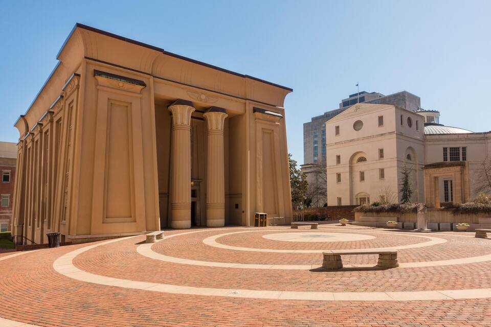 A large beige building with columns and a circular brick courtyard.