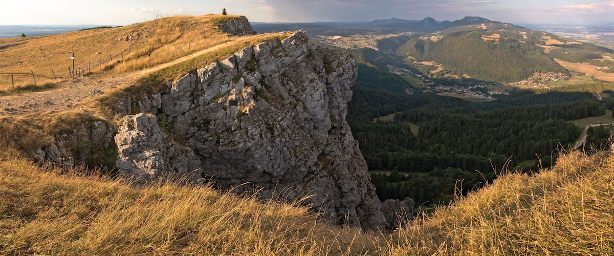A rocky outcrop with a view of a valley and distant mountains.