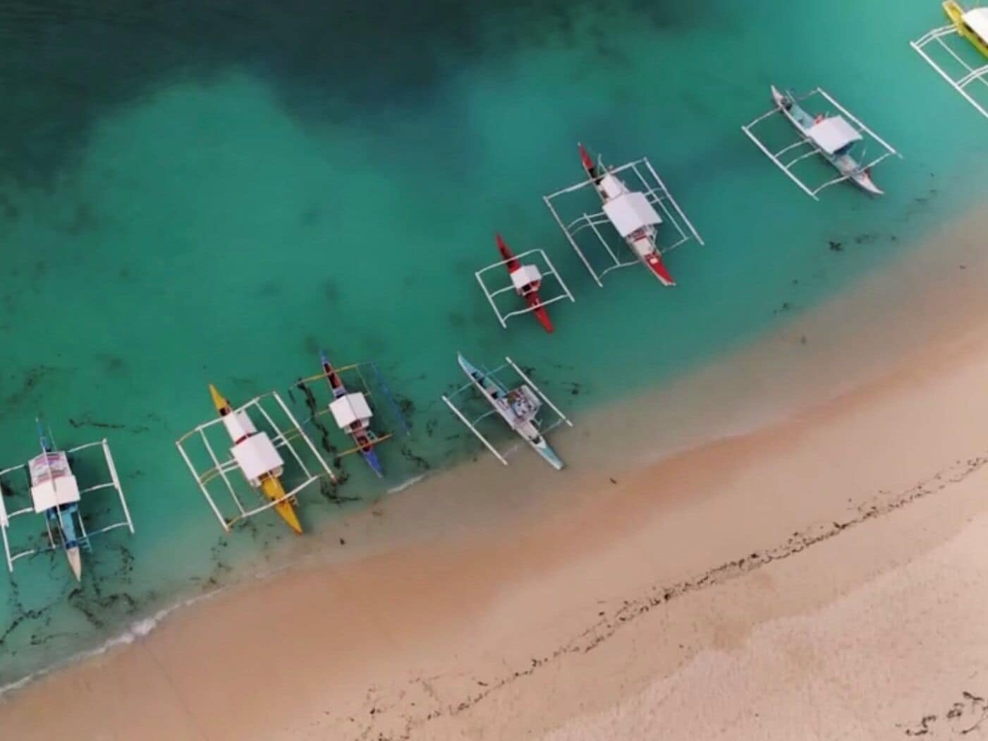 A beach with several boats anchored in shallow water.