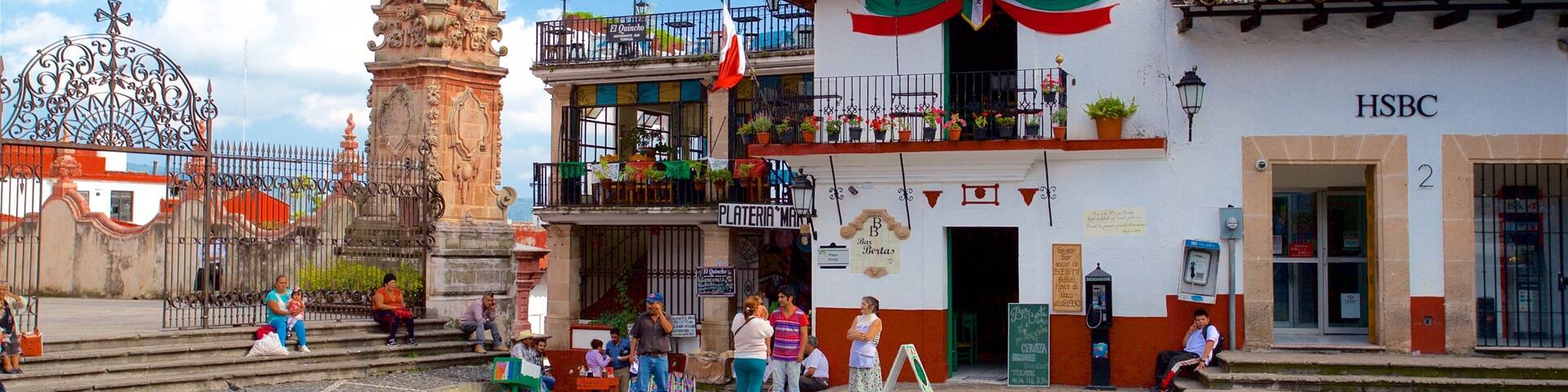 A plaza with a historic monument, a building with a red and white facade, and a HSBC bank.
