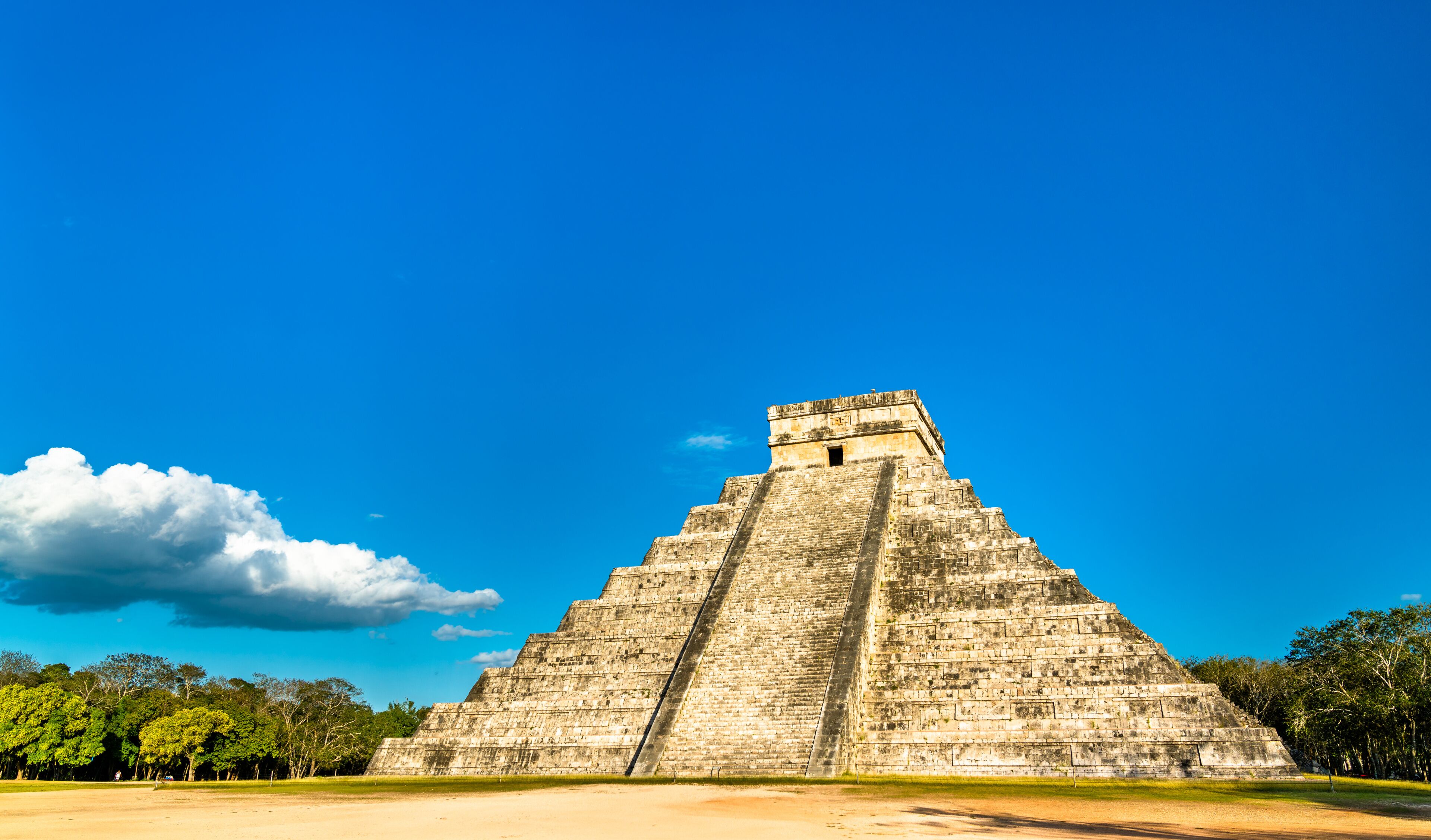 Una gran estructura piramidal con un cielo azul claro y algunas nubes al fondo.