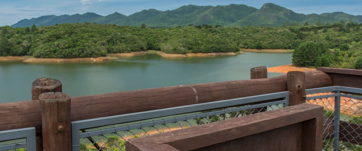 A river with mountains in the background and a wooden fence in the foreground.