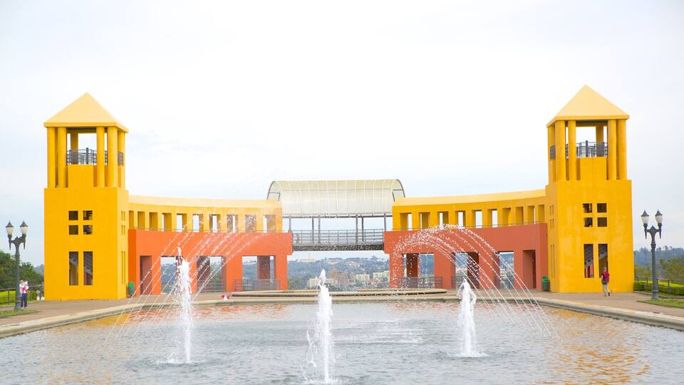 A yellow building with two towers and a fountain in front.