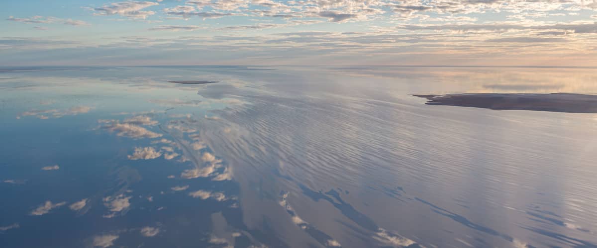 A vast, calm sea with gentle ripples and scattered clouds.
