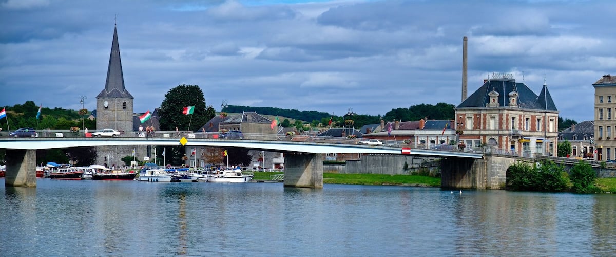 A bridge over a river with boats, a church spire, and historic buildings.