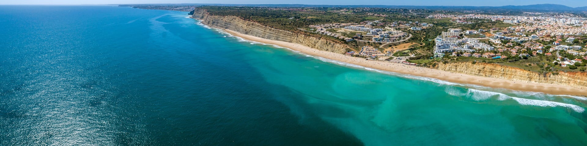 Aerial seascape, of Praia Porto de Mos (Beach and seaside cliff formations along coastline of Lagos city), famous destination in Algarve. South Portugal.