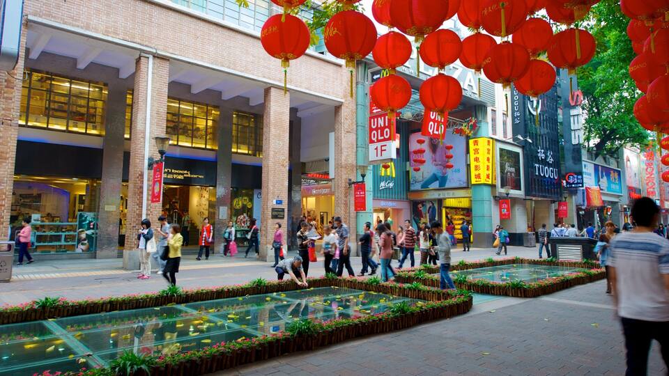 A busy urban street with pedestrians, red lanterns, and storefronts.