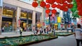 A busy urban street with pedestrians, red lanterns, and storefronts.