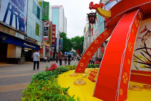 A street with red decorations, yellow pavement, and people walking.