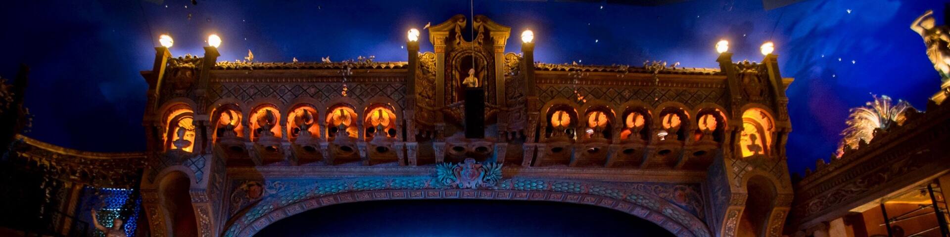 A theater with ornate architecture, a large blue curtain, and decorative lighting.