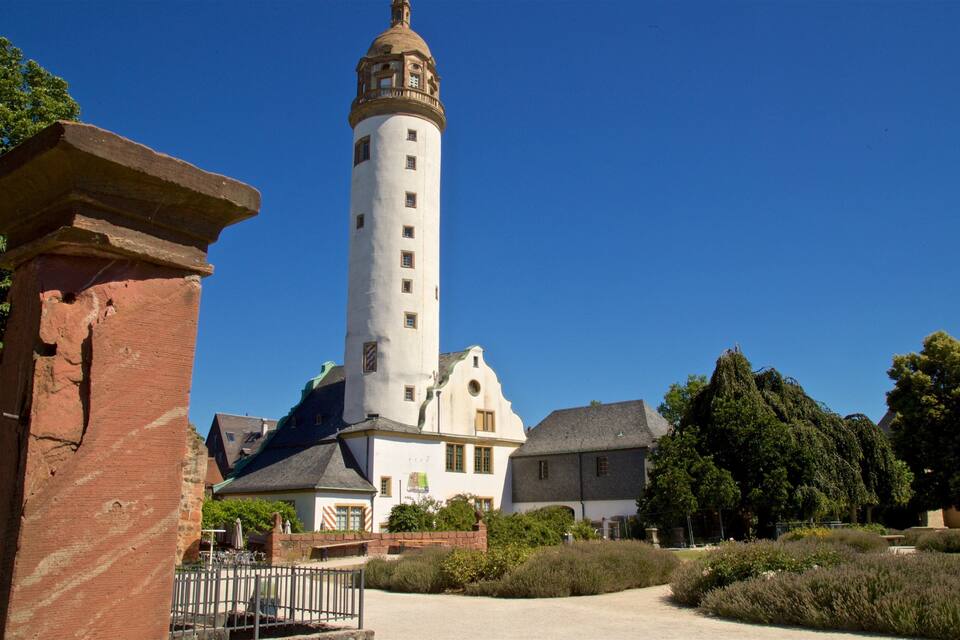 A historic building with a tall tower and a brick structure in the foreground.