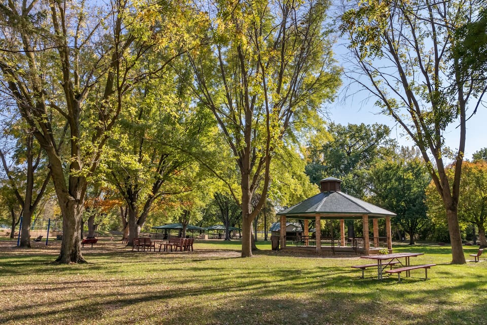 A park with picnic tables, benches, and a gazebo.