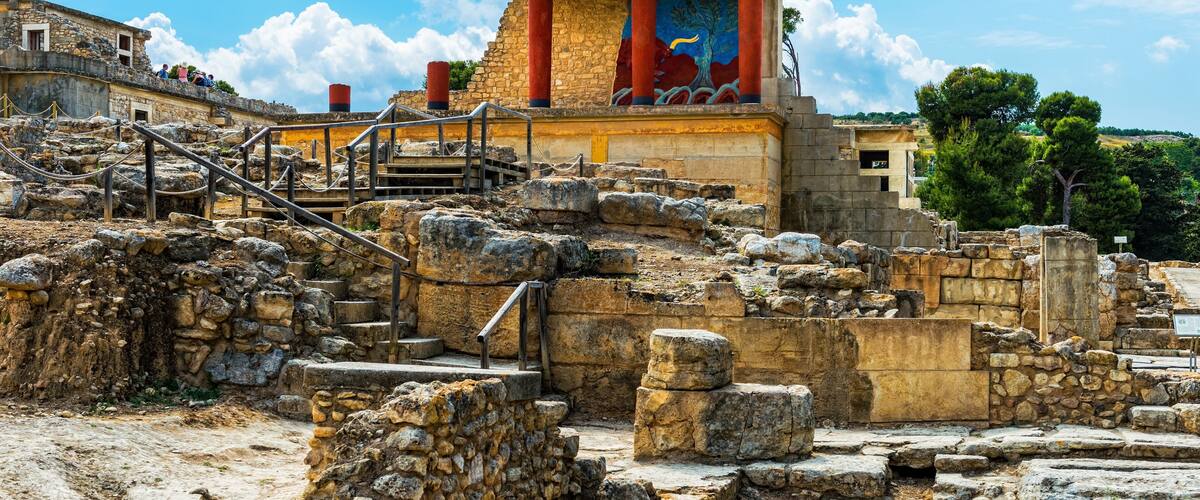 Ancient ruins with stone steps and columns, a mural, and a clear blue sky.
