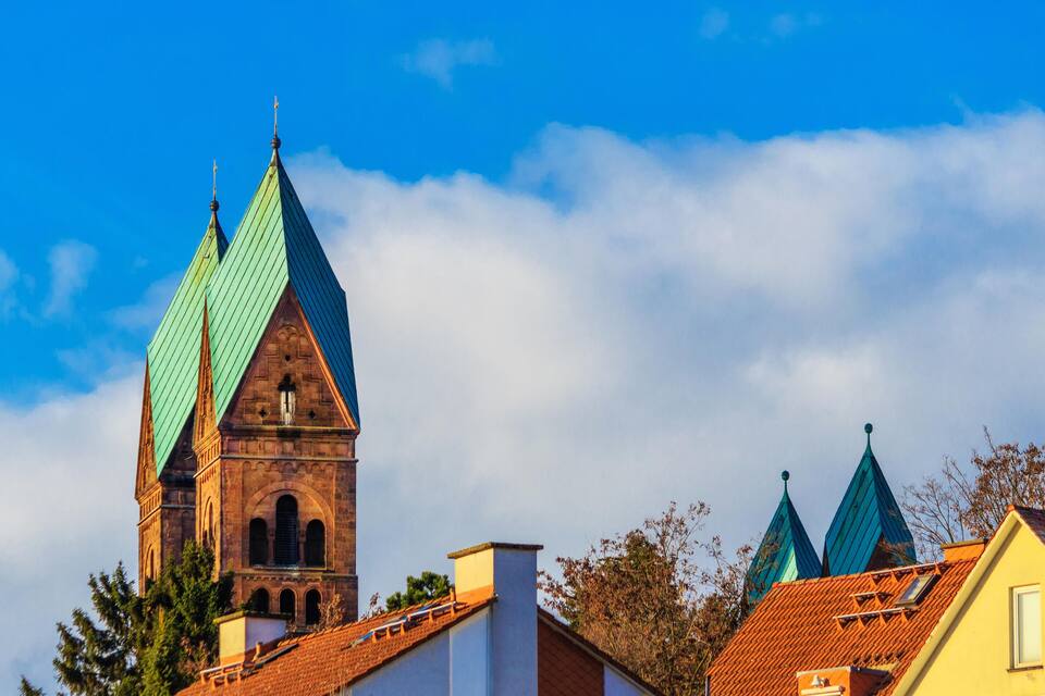 Une église dotée d’un haut clocher et de toits verts en forme de pyramide.