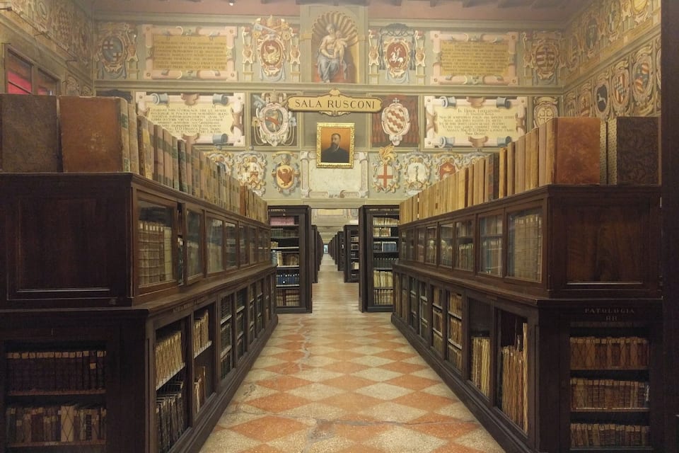 Interior de biblioteca com decoração requintada no teto e piso xadrez.