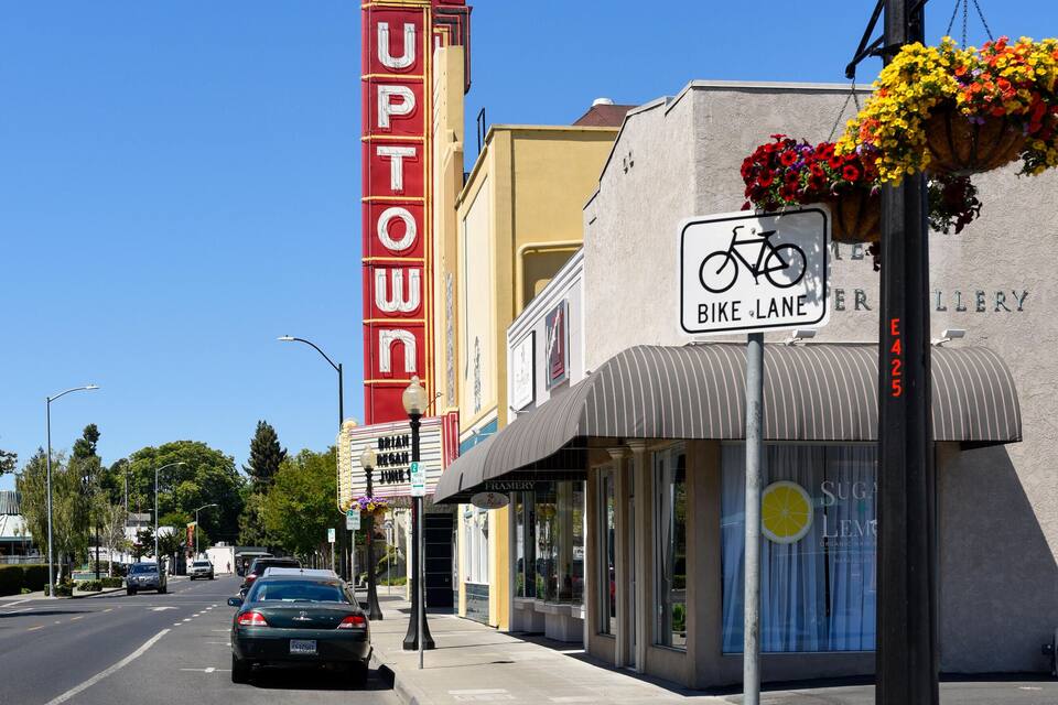 Una calle con un letrero 'UPTOWN', señal de carril bici y un edificio con una maceta de flores.