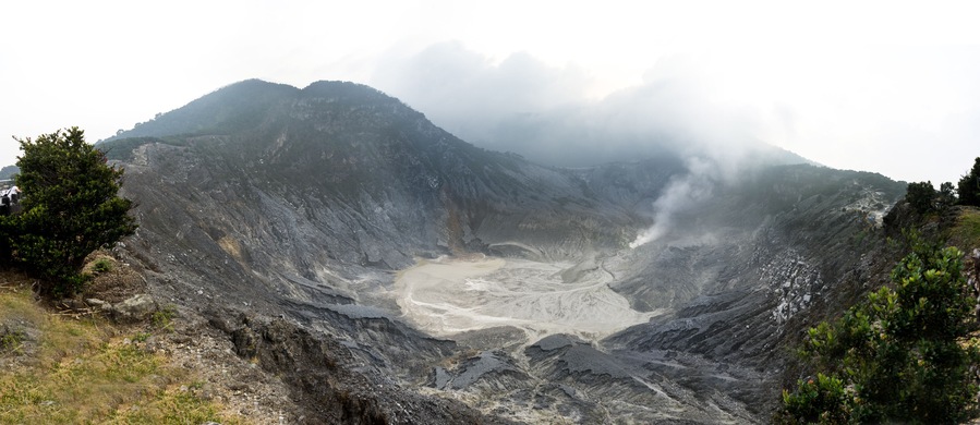 A volcanic crater surrounded by mountains and vegetation.