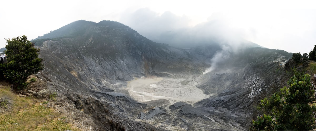 A volcanic crater surrounded by mountains and vegetation.