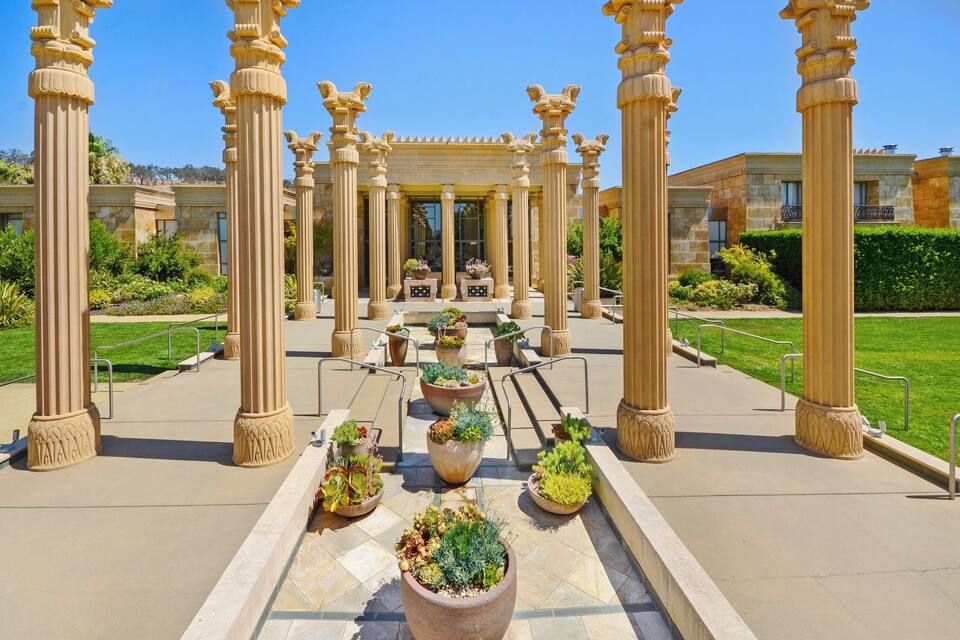 Un jardín con columnas y plantas en macetas.