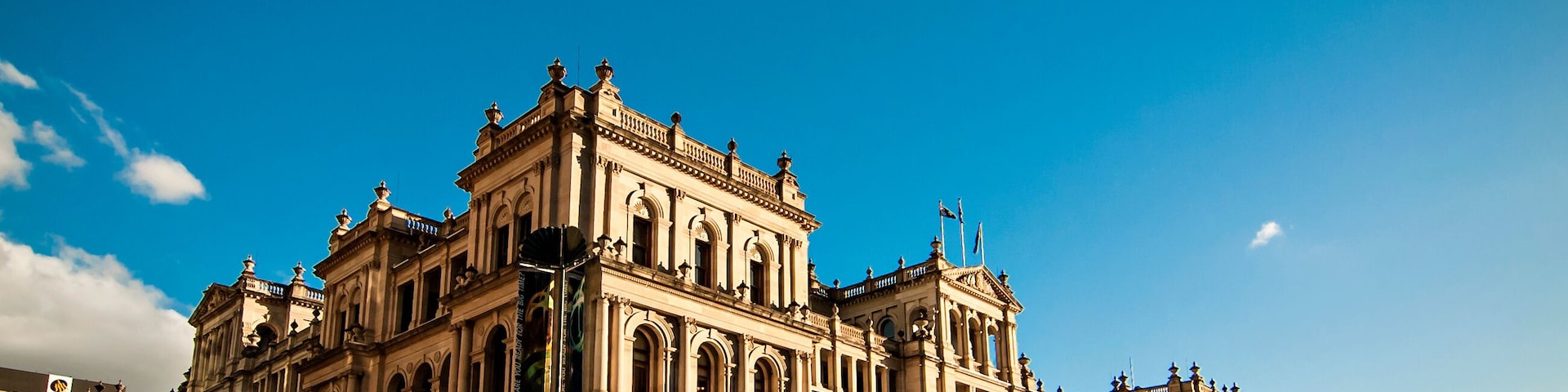 Un edificio grande y ornamentado con múltiples arcos y columnas, rodeado de una calle concurrida llena de peatones.